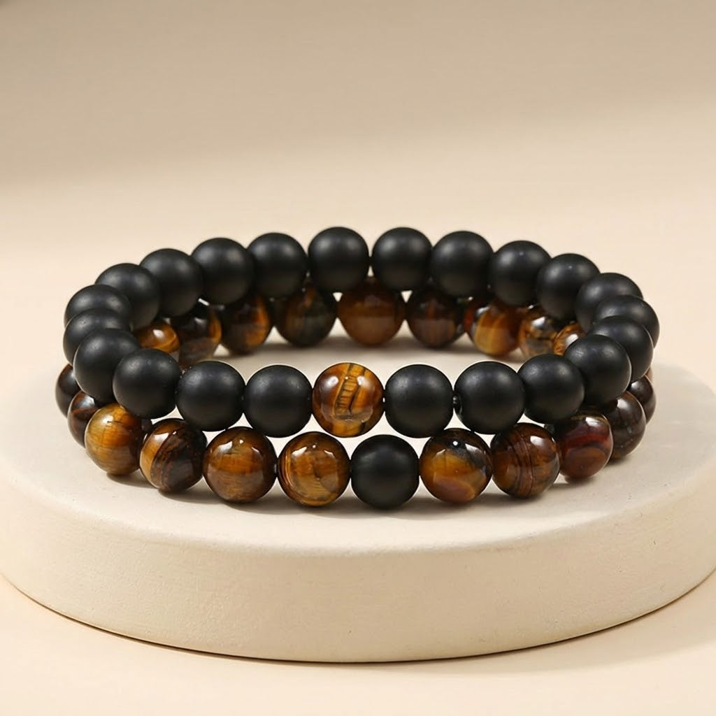 Two beaded bracelets with black and brown beads on a beige background