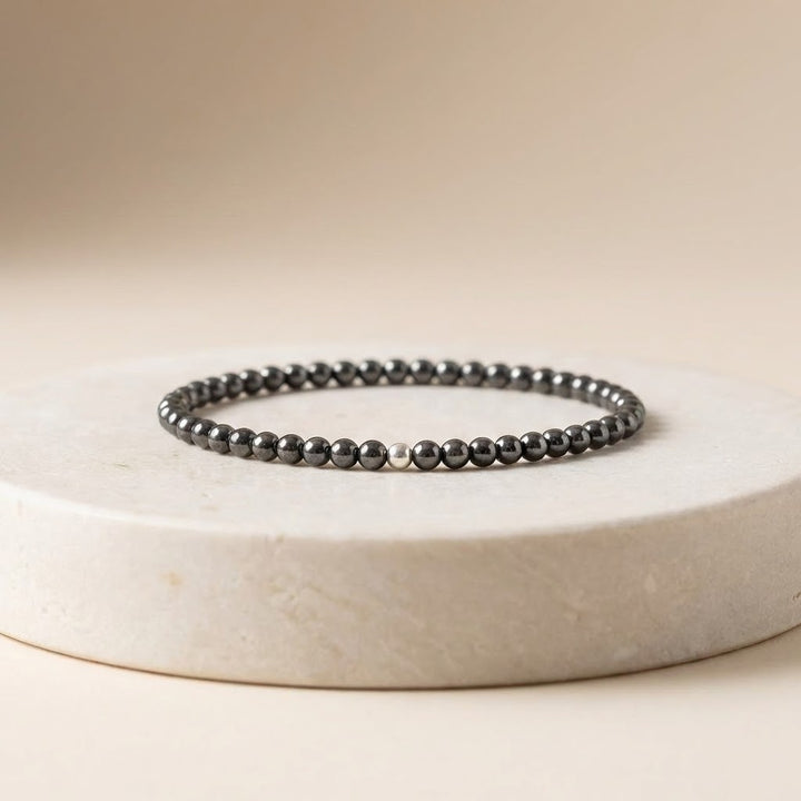 Black beaded bracelet on a white circular stone surface