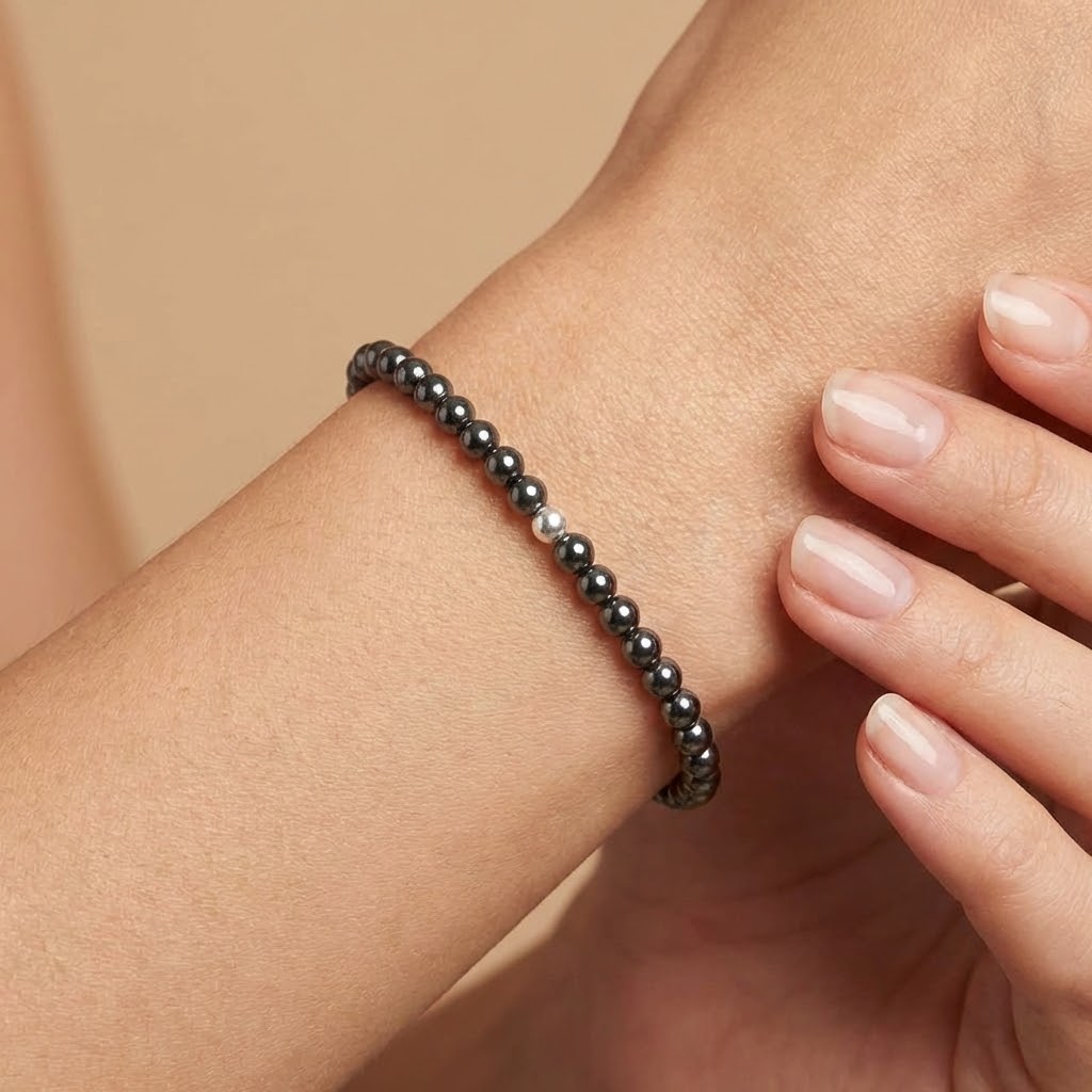 Close-up of a wrist wearing a black beaded bracelet against a beige background