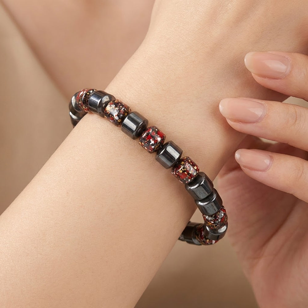 Bracelet with black and red beads on a wrist against a neutral background