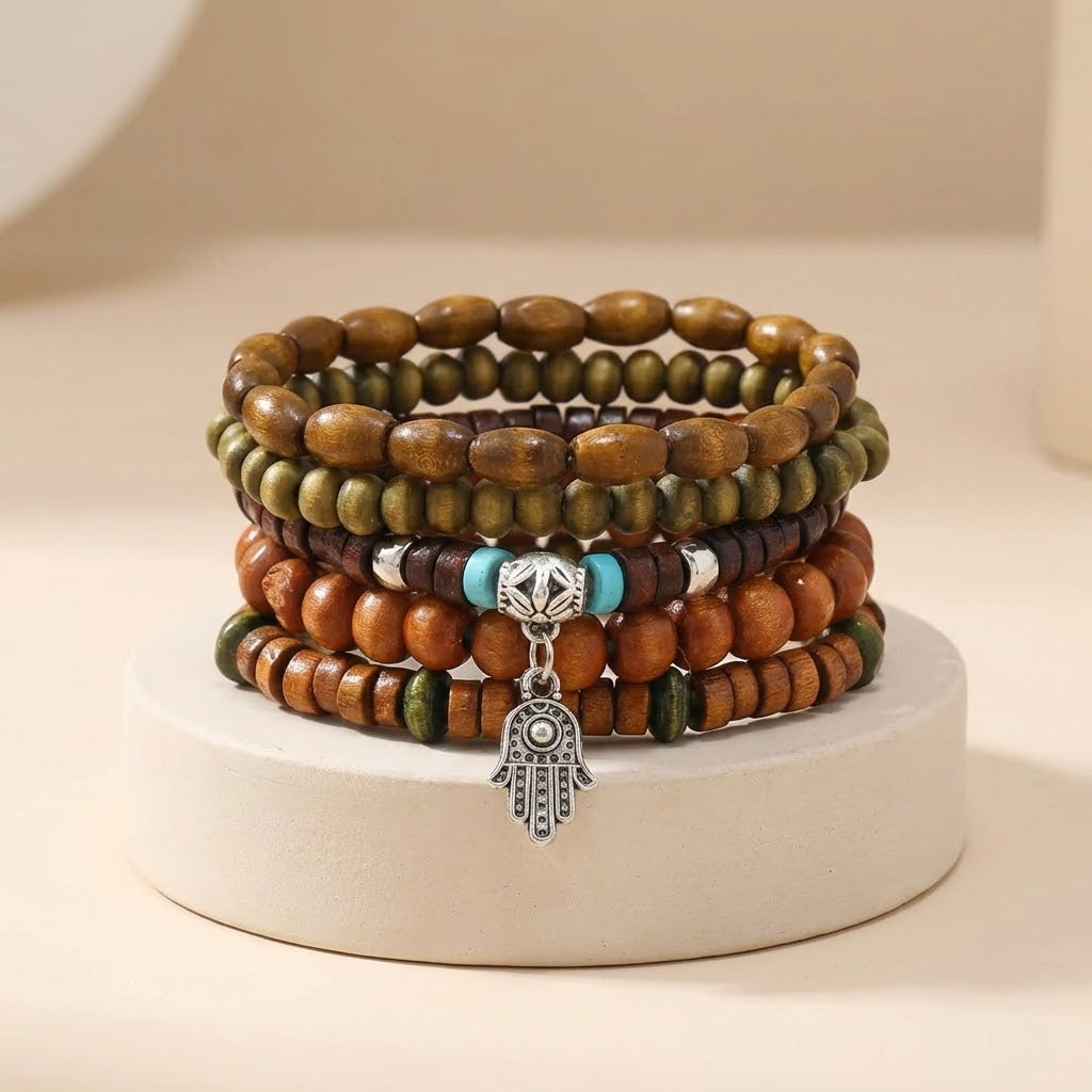 Stack of wooden beaded bracelets with a Hamsa hand charm on a white stand.