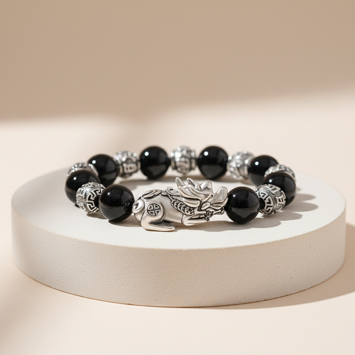 Black beaded bracelet with silver dragon charm on a white base