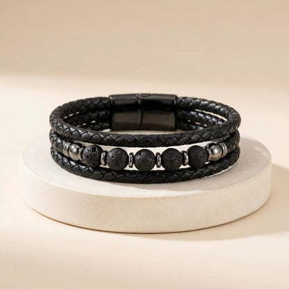 Black braided leather bracelet with beads on a beige background