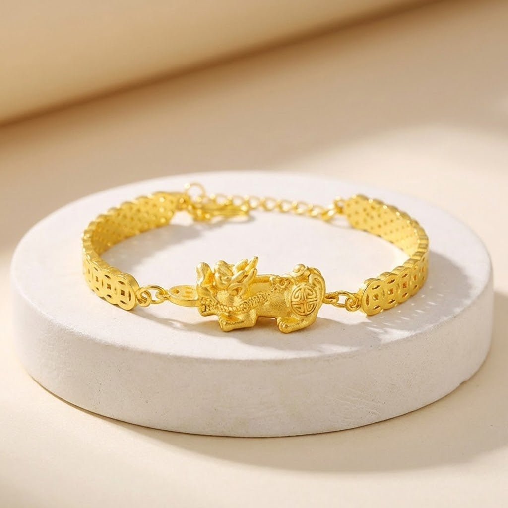 Gold bracelet with a dragon charm on a white stand against a beige background
