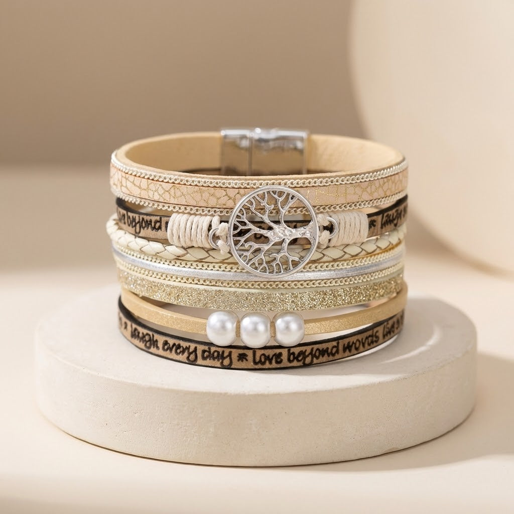 Stack of layered bracelets with tree of life design on a beige background