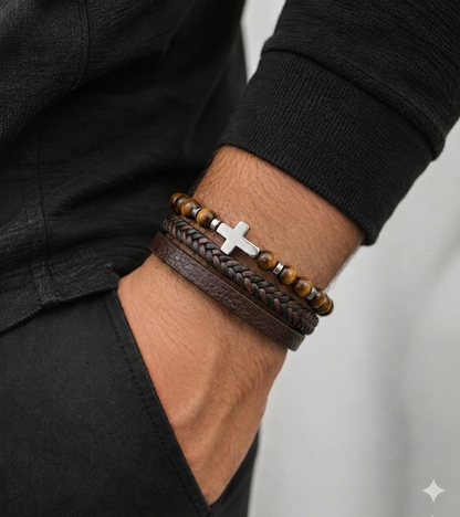 Close-up of a wrist wearing multiple bracelets with a cross charm on a neutral background